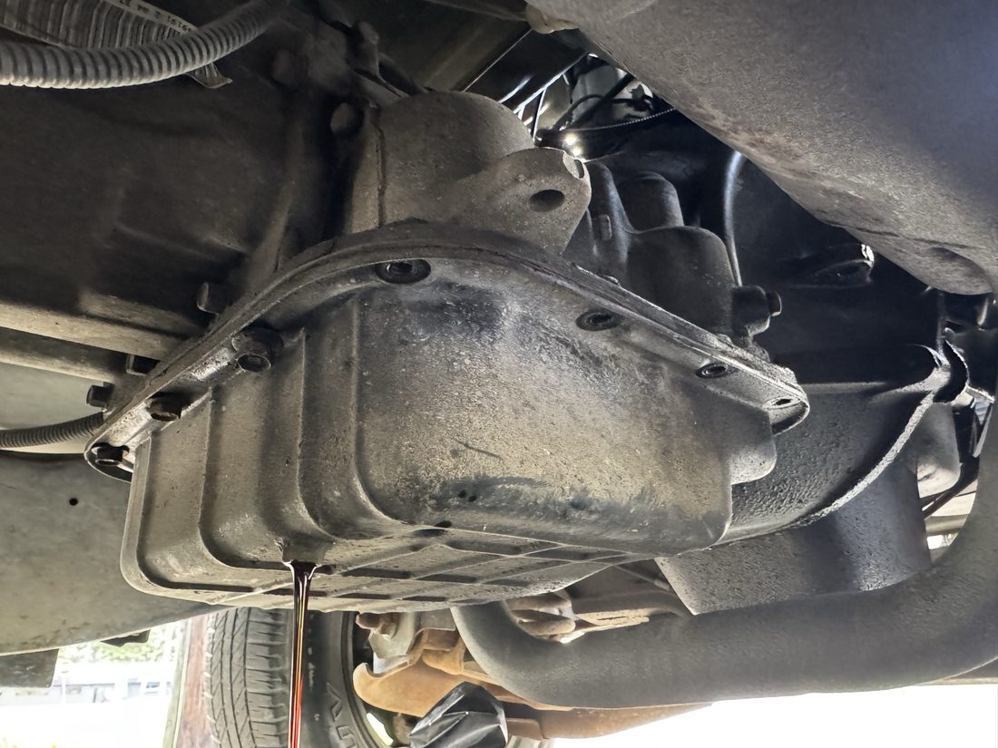 Dark fluid draining from a transmission oil pan during service